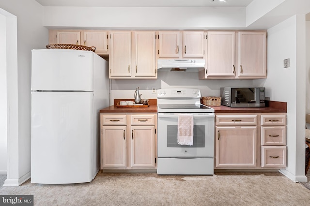 kitchen featuring white appliances, light brown cabinetry, and light carpet