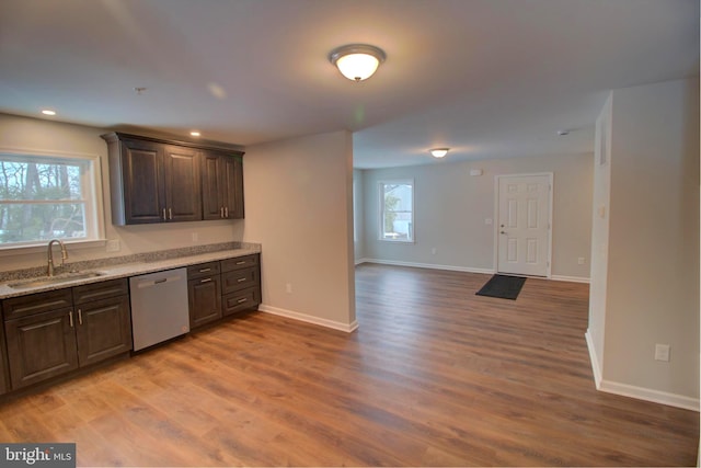 kitchen with dark brown cabinetry, sink, light stone counters, light hardwood / wood-style flooring, and dishwasher