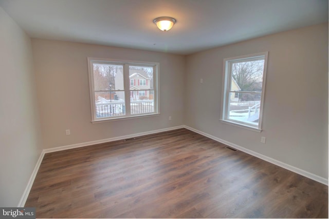 unfurnished room with dark wood-type flooring and plenty of natural light