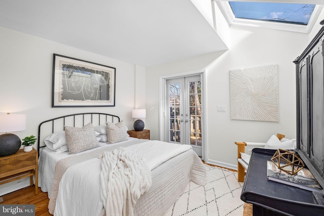 bedroom with light hardwood / wood-style flooring, a skylight, access to outside, and french doors