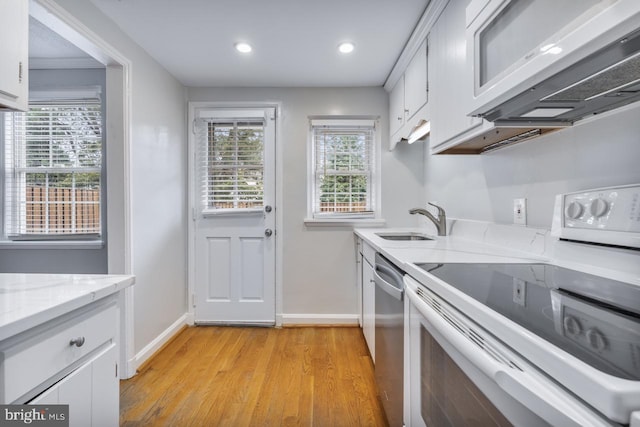 kitchen featuring sink, white electric range, white cabinetry, light hardwood / wood-style floors, and stainless steel dishwasher