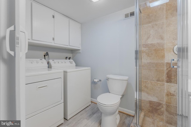 bathroom featuring toilet, a shower with shower door, hardwood / wood-style floors, and washer and dryer