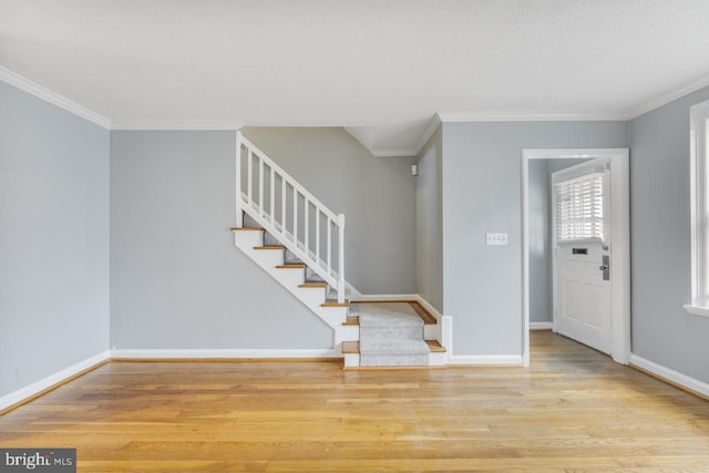 foyer with ornamental molding and light hardwood / wood-style flooring