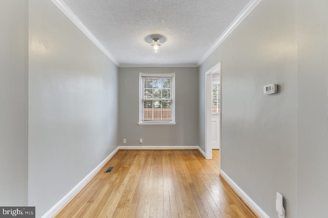 empty room featuring crown molding, a textured ceiling, and light wood-type flooring