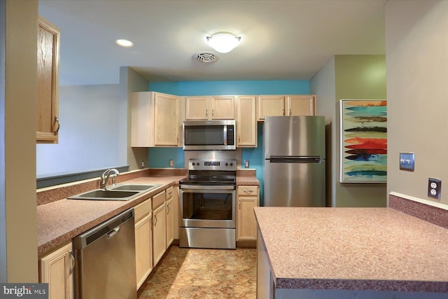 kitchen with appliances with stainless steel finishes, sink, light brown cabinets, and kitchen peninsula