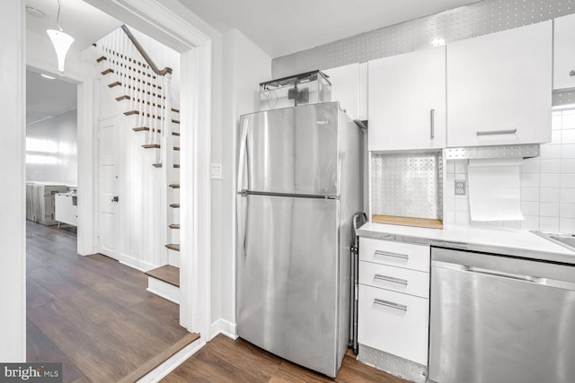 kitchen featuring stainless steel appliances, white cabinetry, dark wood-type flooring, and decorative backsplash