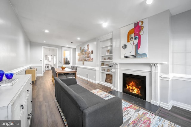 living room with dark wood-type flooring and built in shelves