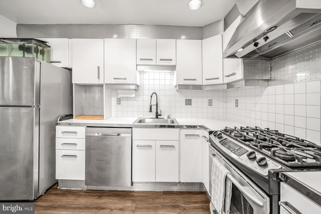 kitchen with wall chimney exhaust hood, sink, white cabinetry, tasteful backsplash, and stainless steel appliances