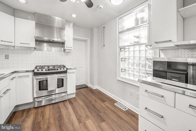 kitchen with stainless steel gas range oven, white cabinetry, wall chimney range hood, and dark hardwood / wood-style flooring