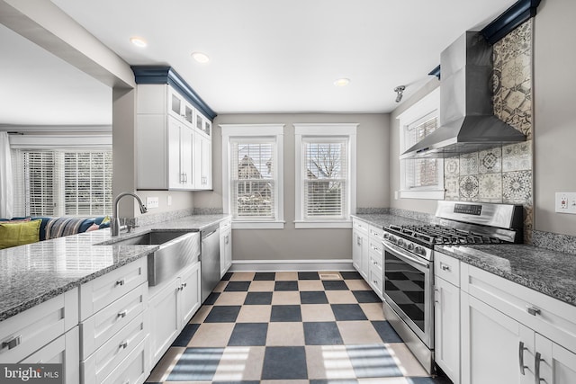 kitchen featuring appliances with stainless steel finishes, sink, white cabinets, and wall chimney exhaust hood