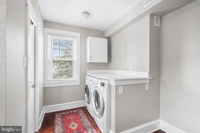 washroom featuring cabinets, washing machine and dryer, and dark wood-type flooring