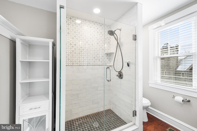 bathroom with hardwood / wood-style flooring, toilet, and an enclosed shower