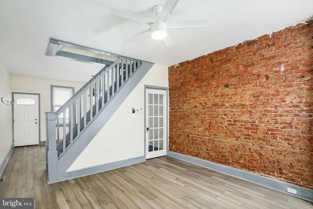 spare room with light hardwood / wood-style floors, brick wall, and ceiling fan