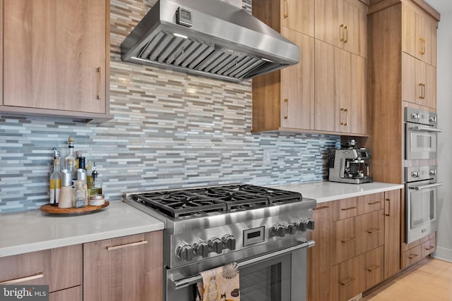 kitchen featuring wall chimney range hood, backsplash, stainless steel appliances, and light hardwood / wood-style floors