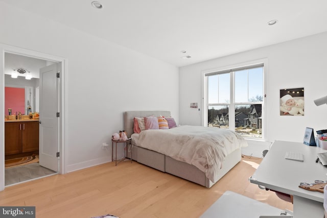 bedroom with ensuite bath, sink, and light hardwood / wood-style floors