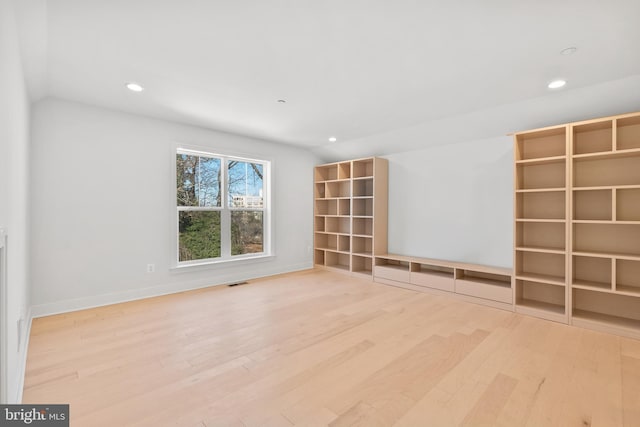 spare room featuring vaulted ceiling and light wood-type flooring