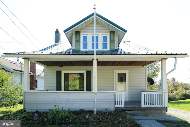 bungalow featuring covered porch, metal roof, and a chimney