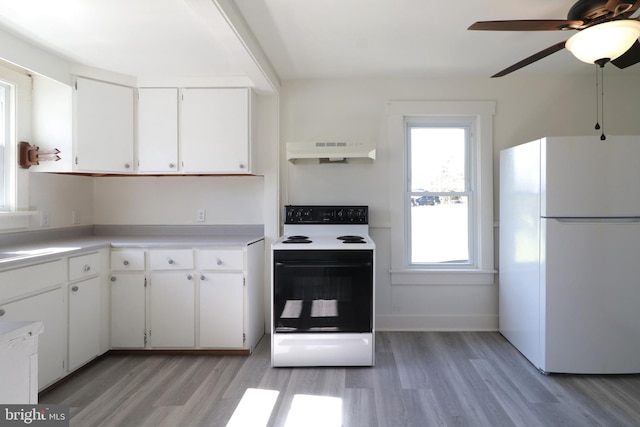 kitchen featuring light countertops, electric range oven, freestanding refrigerator, white cabinets, and under cabinet range hood