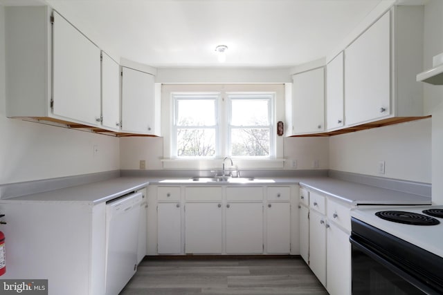 kitchen with light wood finished floors, light countertops, white cabinets, white dishwasher, and a sink