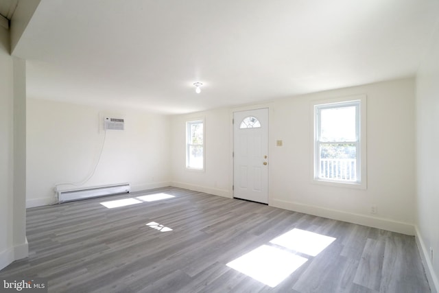 entryway with baseboards, a baseboard heating unit, wood finished floors, and a wall mounted AC