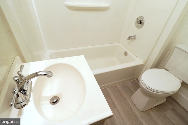 bathroom featuring  shower combination, wood finished floors, a sink, and toilet