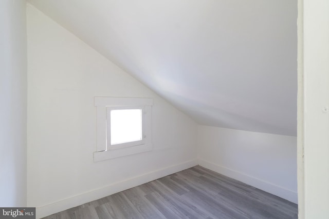 additional living space with vaulted ceiling, wood finished floors, and baseboards