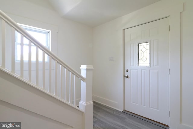 foyer entrance featuring stairs, wood finished floors, and baseboards