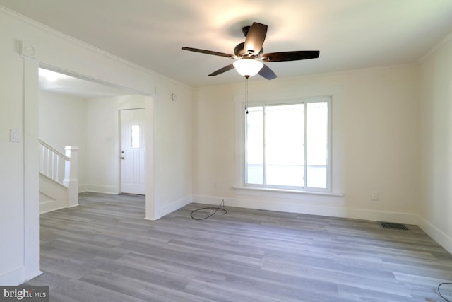 spare room with light wood finished floors, baseboards, visible vents, stairs, and crown molding