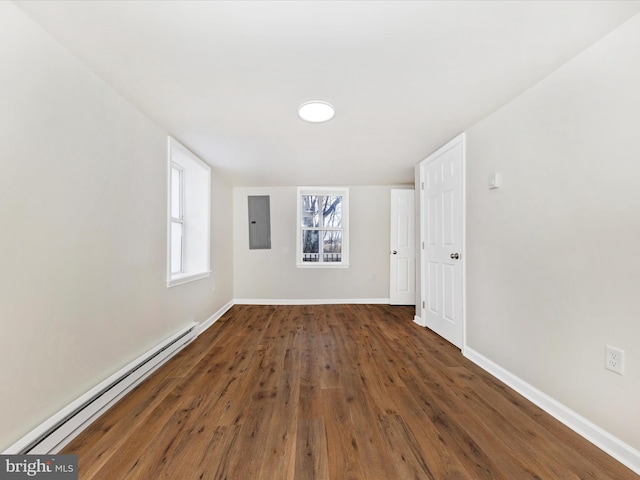 spare room featuring baseboard heating, plenty of natural light, dark hardwood / wood-style flooring, and electric panel