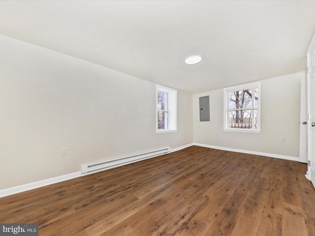 unfurnished room with dark hardwood / wood-style flooring, a baseboard heating unit, a wealth of natural light, and electric panel