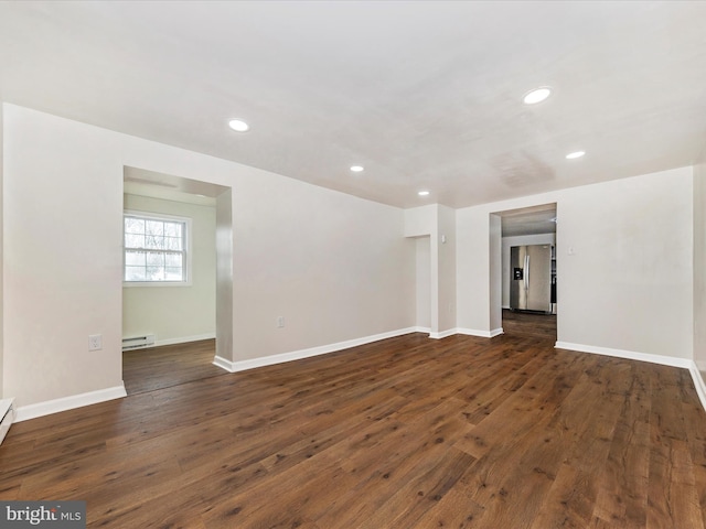 empty room featuring a baseboard heating unit and dark hardwood / wood-style flooring