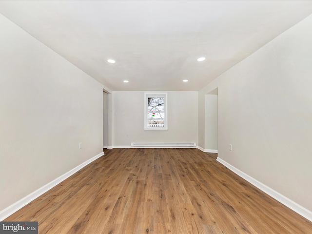 unfurnished room with hardwood / wood-style flooring and a baseboard radiator