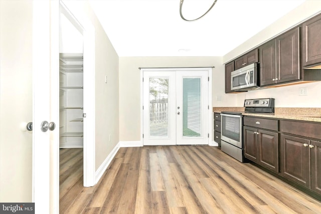 kitchen with french doors, appliances with stainless steel finishes, dark brown cabinetry, and light wood-style floors