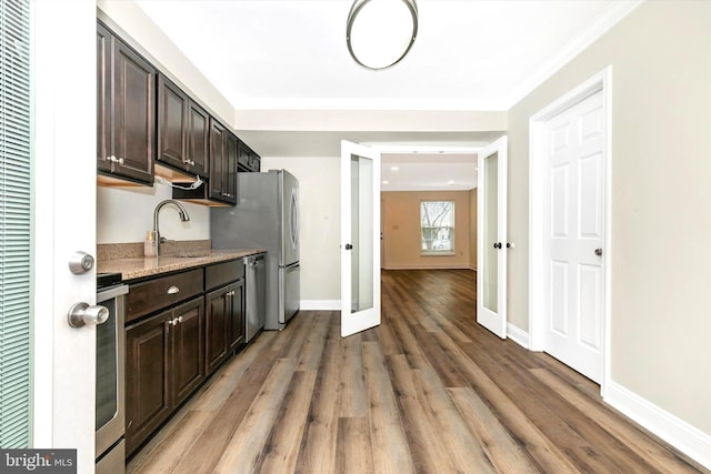 kitchen featuring dark brown cabinetry, wood finished floors, a sink, stainless steel dishwasher, and range