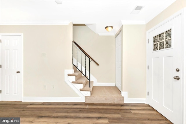 entrance foyer featuring stairs, crown molding, wood finished floors, and baseboards