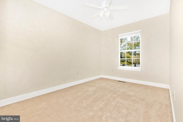 carpeted empty room featuring baseboards, visible vents, and a ceiling fan