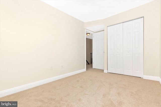 unfurnished bedroom with carpet, a closet, and baseboards