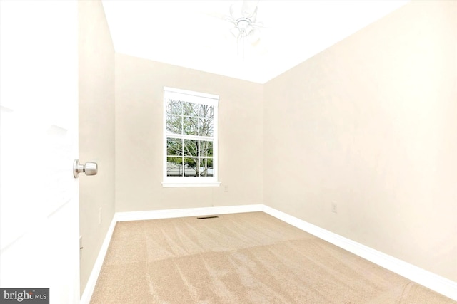 empty room with carpet flooring, visible vents, and baseboards