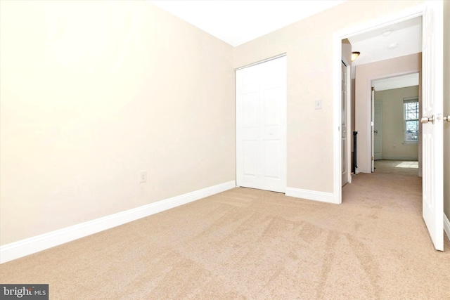 unfurnished bedroom featuring a closet, light carpet, and baseboards