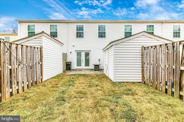 rear view of house featuring french doors, a fenced backyard, and a lawn