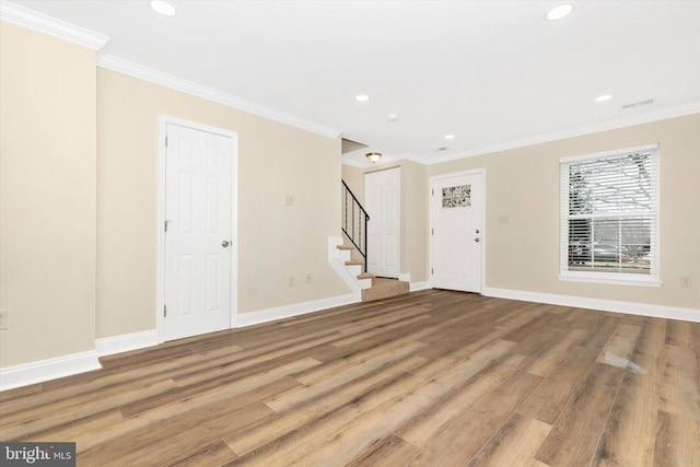 interior space featuring baseboards, stairway, wood finished floors, and ornamental molding