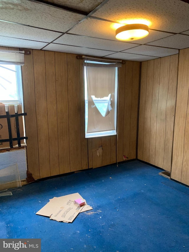 empty room featuring a paneled ceiling and wood walls