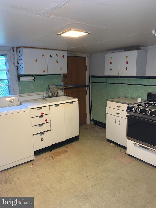 kitchen featuring washer / clothes dryer, white cabinetry, and range with gas stovetop