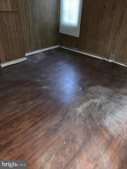 spare room featuring dark hardwood / wood-style flooring and wooden walls