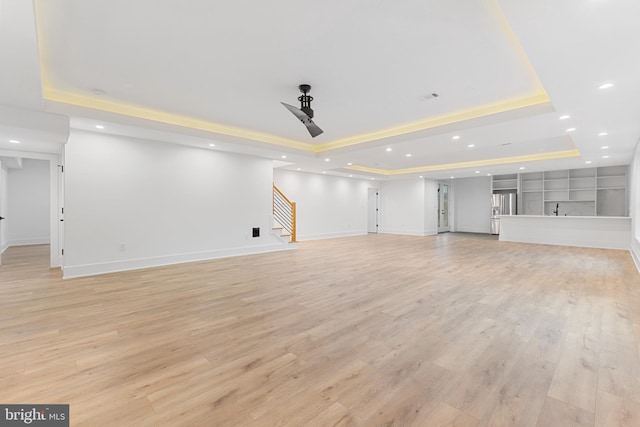 unfurnished living room featuring a tray ceiling and light wood-type flooring