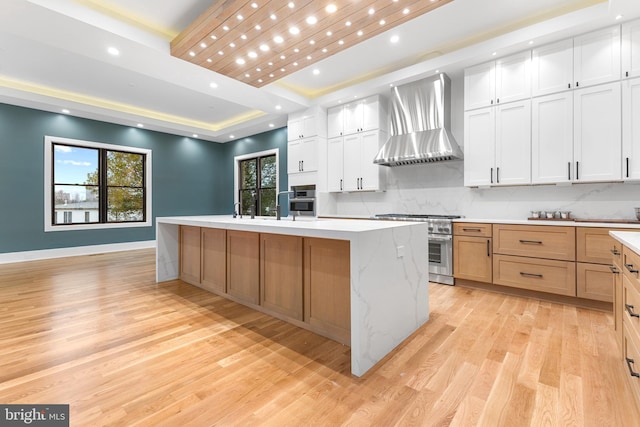 kitchen with white cabinetry, a large island, high end stainless steel range, and wall chimney range hood