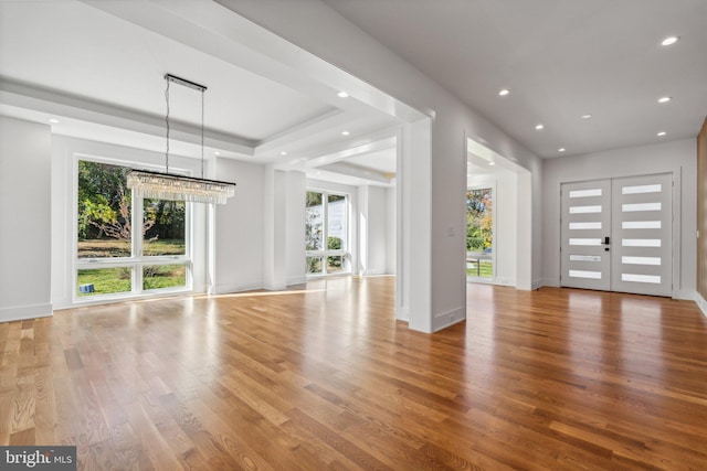 unfurnished living room with french doors, wood-type flooring, and a tray ceiling