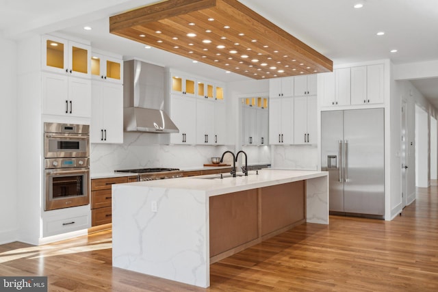 kitchen with white cabinetry, a spacious island, wall chimney exhaust hood, and appliances with stainless steel finishes