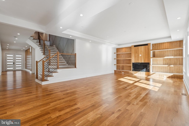 unfurnished living room featuring french doors, a tray ceiling, and hardwood / wood-style floors