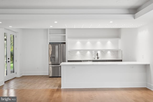 kitchen featuring sink, light hardwood / wood-style flooring, stainless steel fridge, kitchen peninsula, and white cabinets